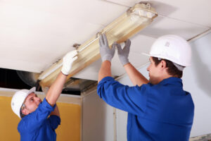 two electricians repairing office lighting